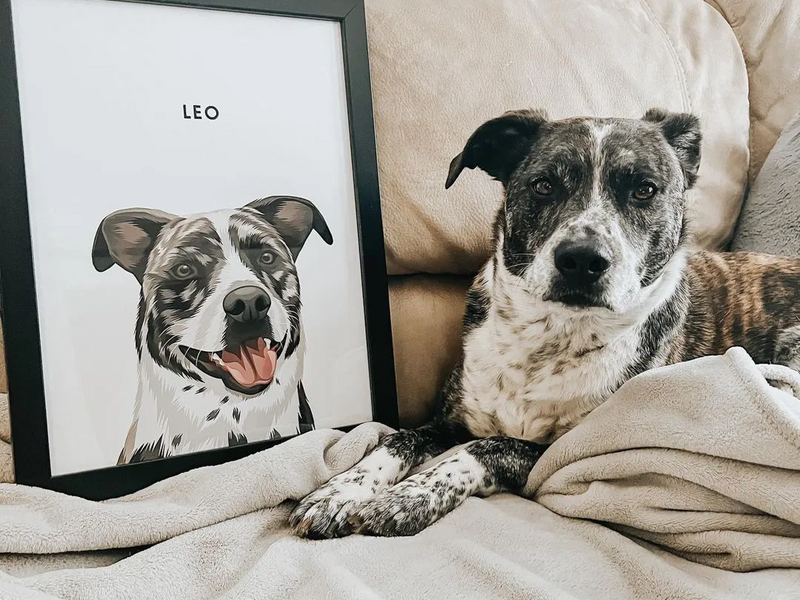 Brindle dog relaxing beside its framed modern portrait